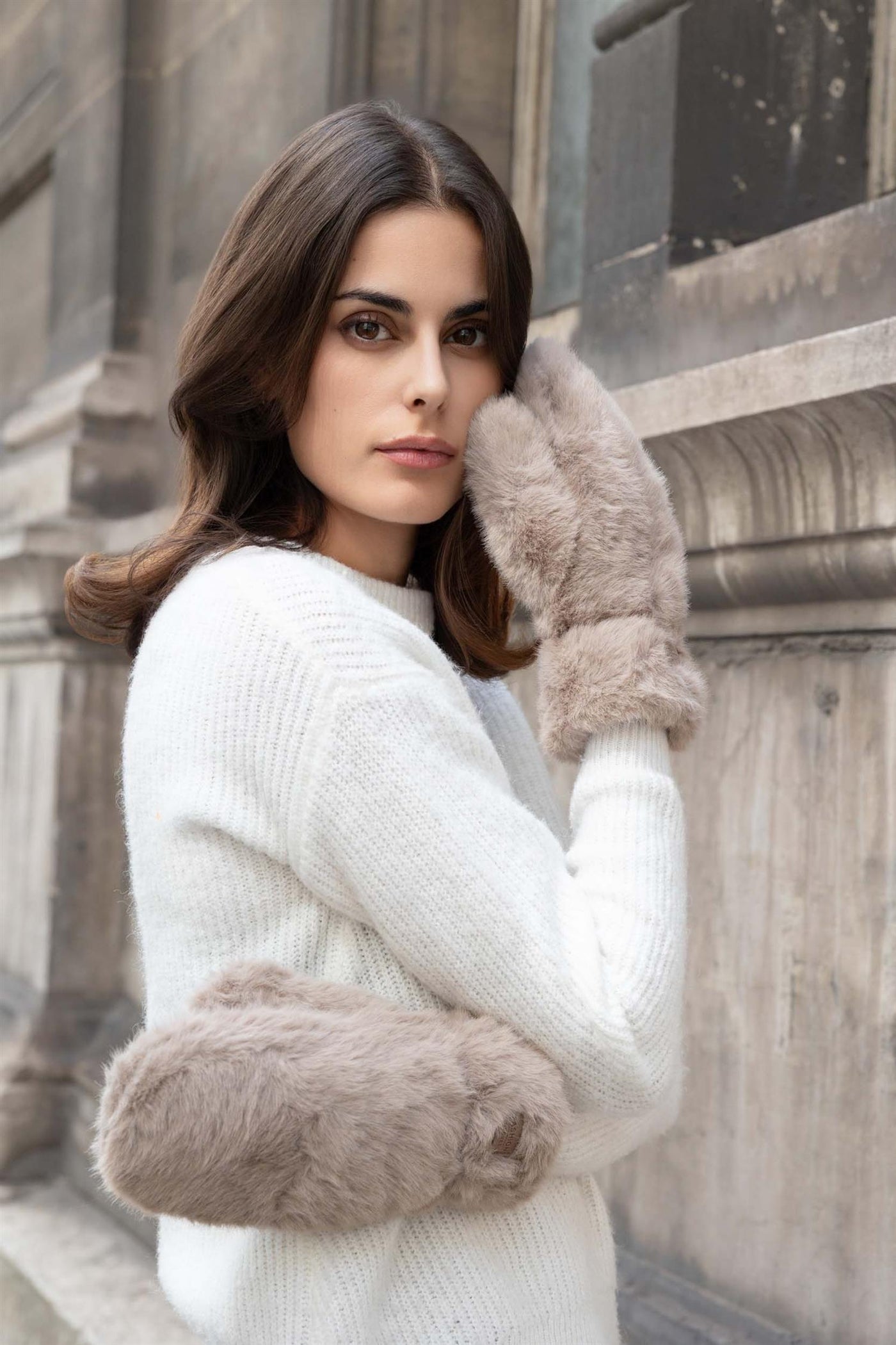 Person med myke, lyse votter i fuskeples som dekker hånd og håndledd.