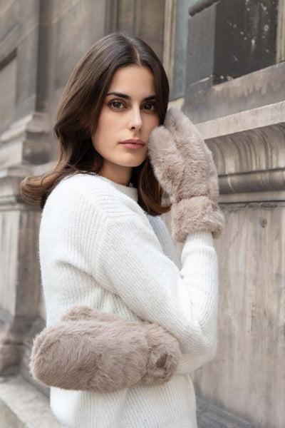 Person med myke, lyse votter i fuskeples som dekker hånd og håndledd.