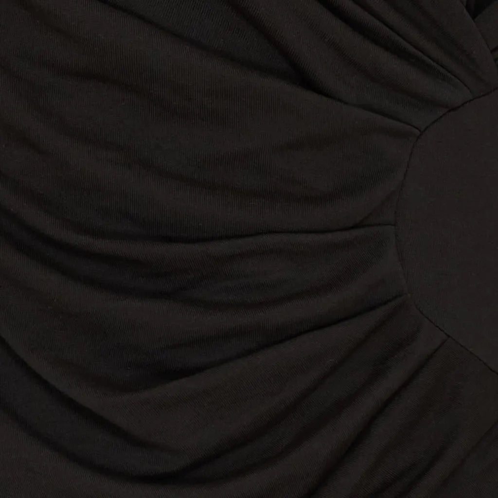 Nærbilde av svart stoff med draperingsdetaljer, som antyder tekstur og dybde i designet.