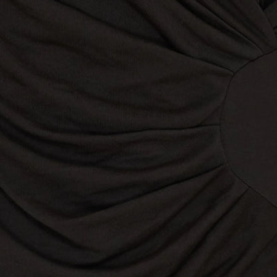 Nærbilde av svart stoff med draperingsdetaljer, som antyder tekstur og dybde i designet.