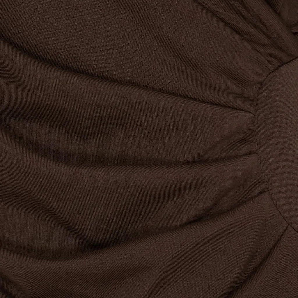 Nærbilde av brun, drapert stoff med tekstur, del av MdcPrimrose bluse.