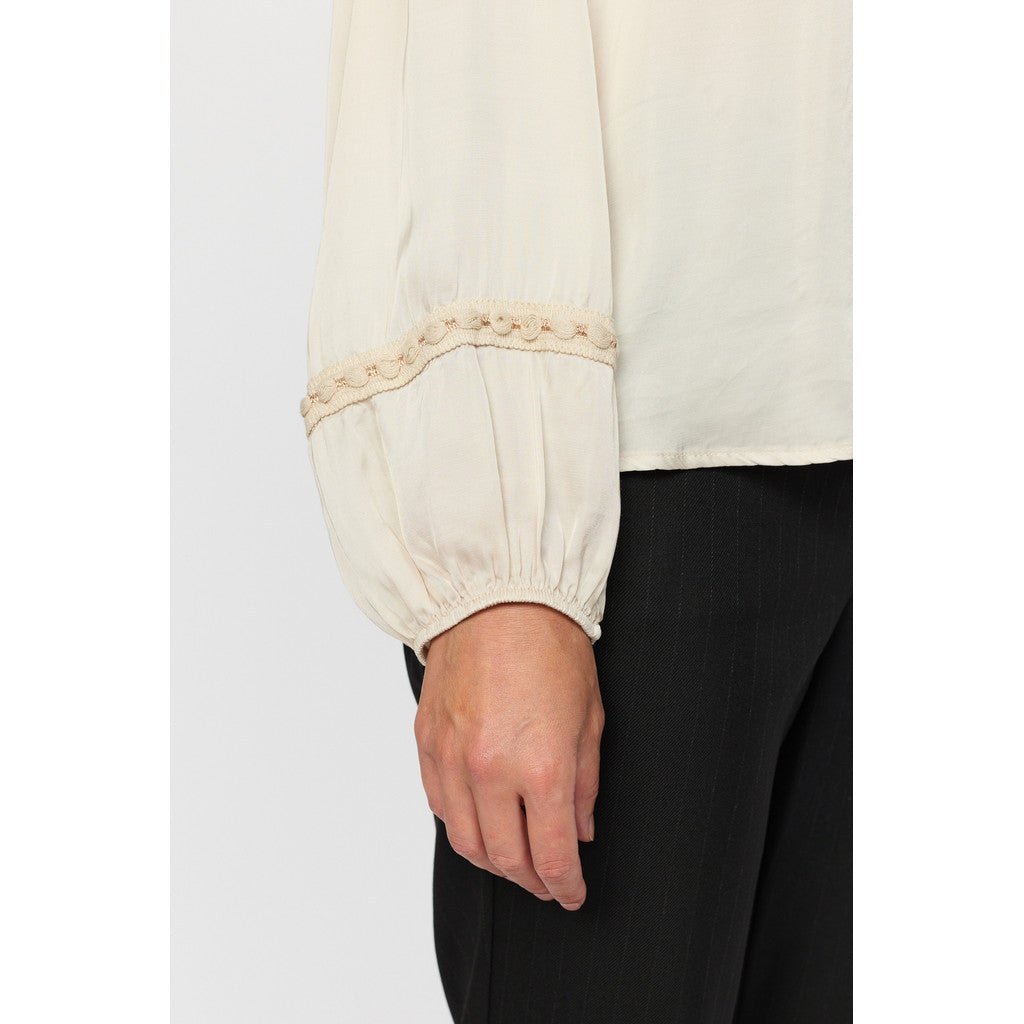 Lys bluseerm med elastisk mansjett og blondedetaljer.