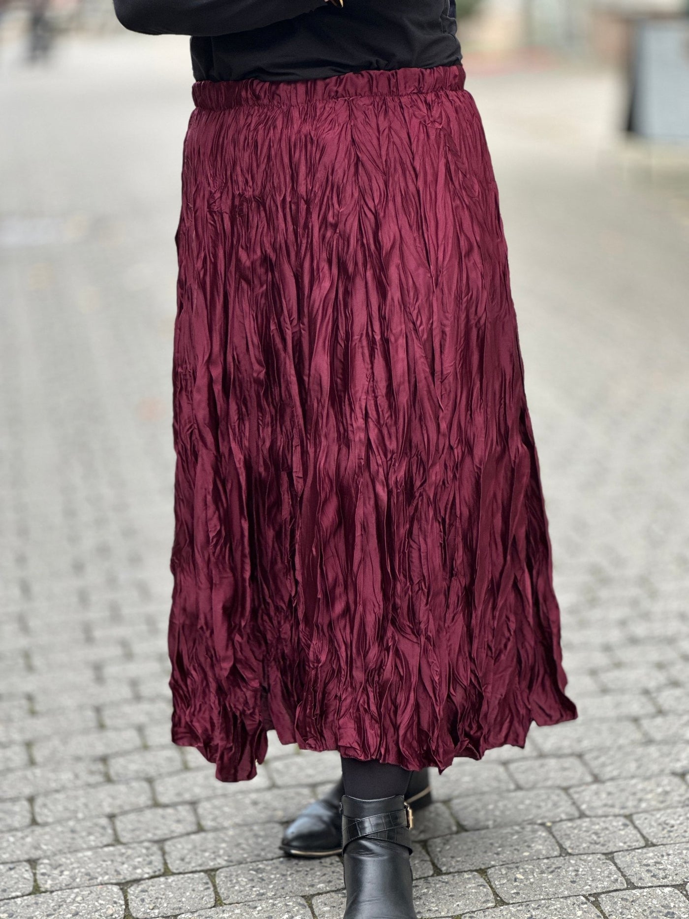 Burgunderfarget satengskjørt med krinklet tekstur, midi-lengde. Brukes med svarte støvler.