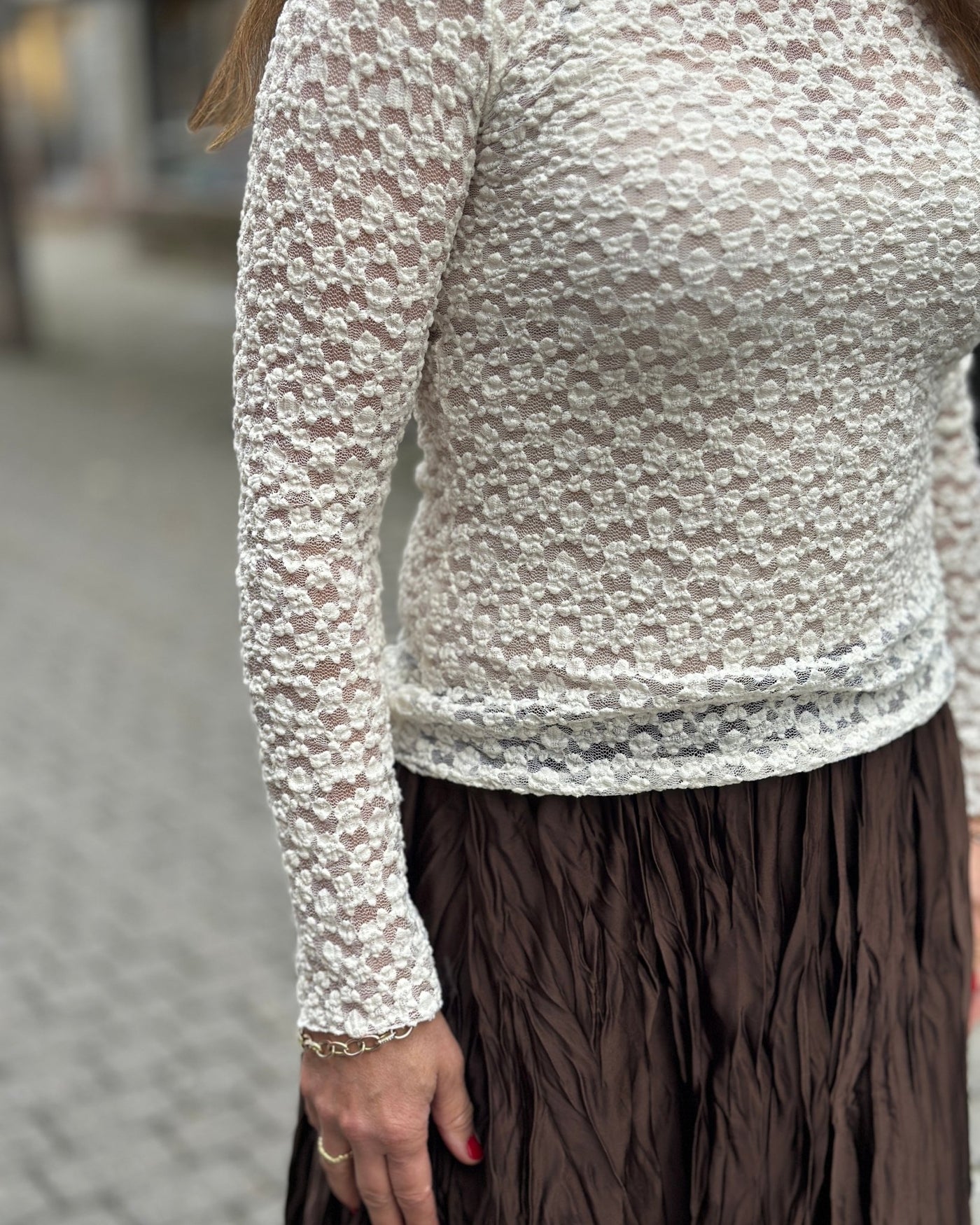 Tettsittende, langermet topp med blondeaktig mønster, kombinert med brun skjørt.