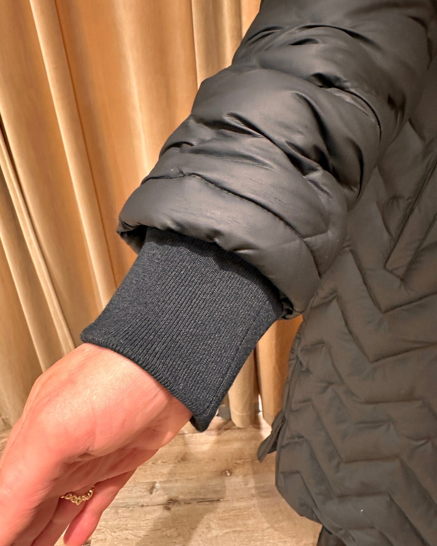 Nærbilde av ermet på en quiltet kåpe med ribbestrikket mansjett og boblemønster.