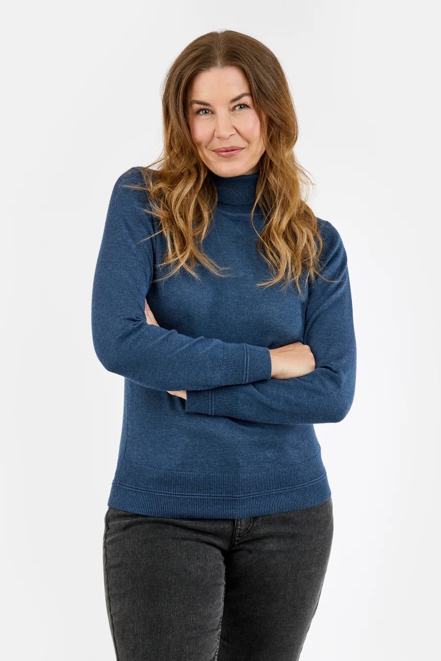 Blå genser med høy hals, ribbestrikket kant nederst og lange ermer, båret av en kvinne.