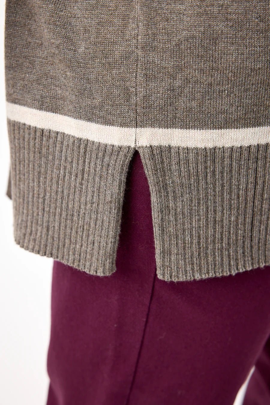 Grå genser med hvite striper, ribbestrikket kant og en liten splitt på siden.