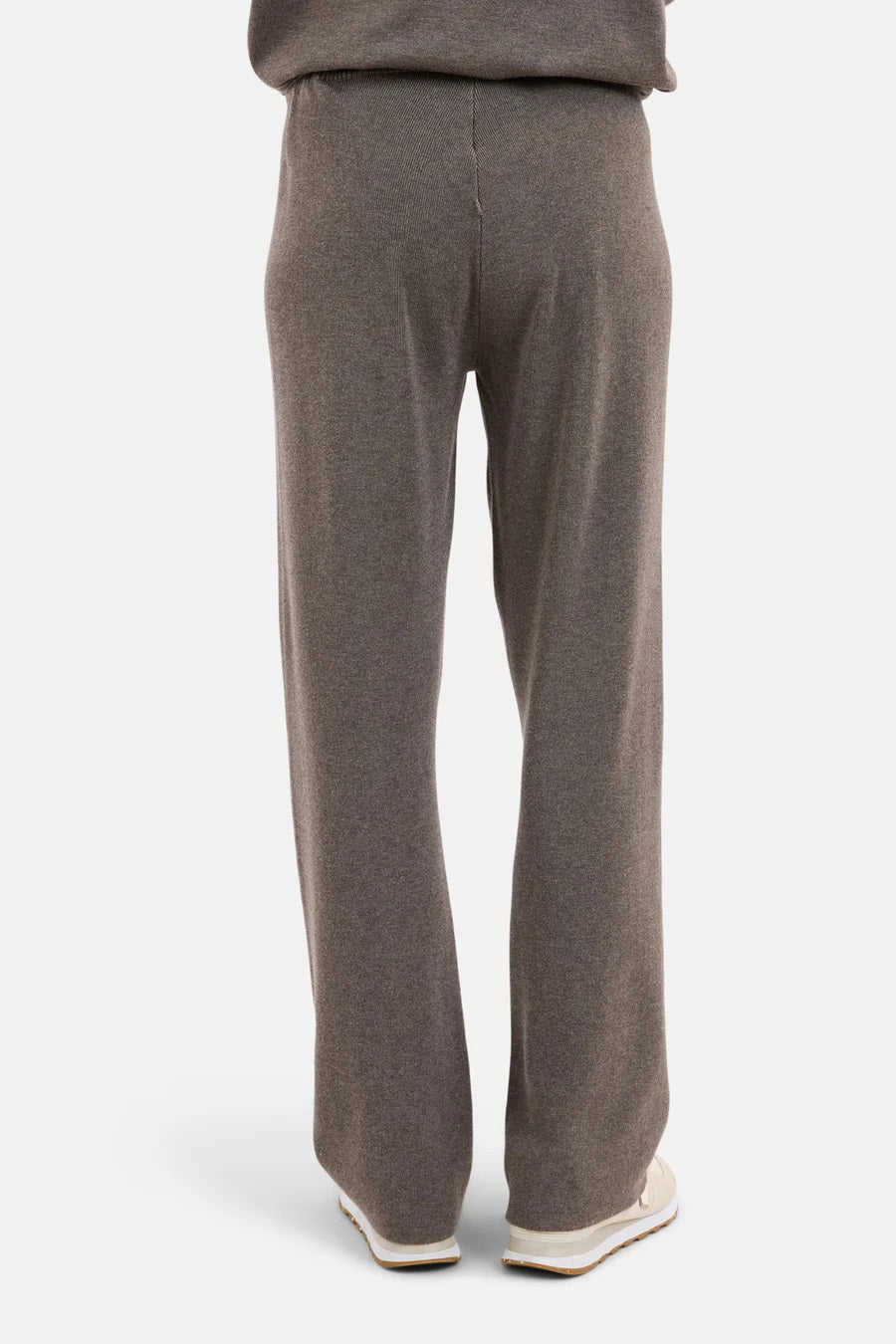 Bakside av brune bukser med elastisk linning, brede ben og løs passform, kombinert med hvite sko.