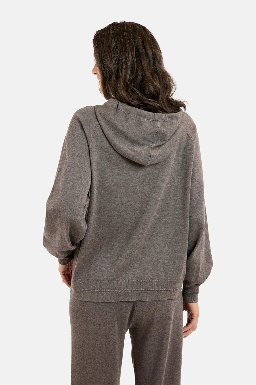 Person iført grå hettegenser med hette og lange ermer, sett bakfra, løs passform, myk tekstur.