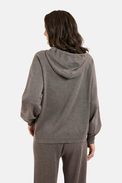 Person iført grå hettegenser med hette og lange ermer, sett bakfra, løs passform, myk tekstur.