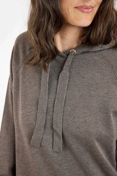 Nærbilde av brun hettegenser med snorer, lange ermer og løs passform, båret av kvinne.