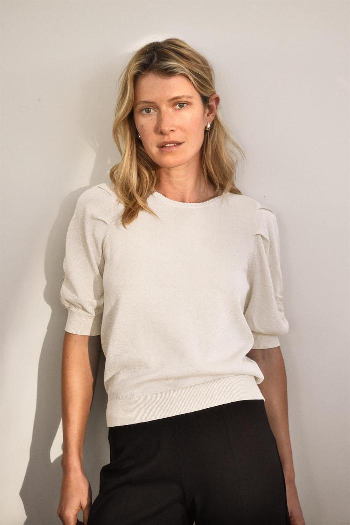 Lys genser med rund hals, korte posete ermer og ribbestrikket kant.