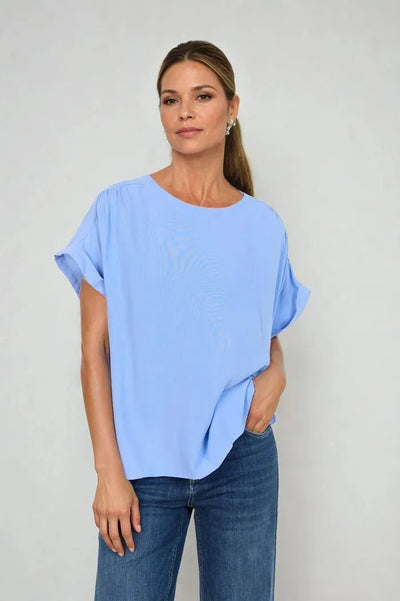 Lys blå topp med korte ermer og rund hals, løs passform, kombinert med jeans for en uformell stil.