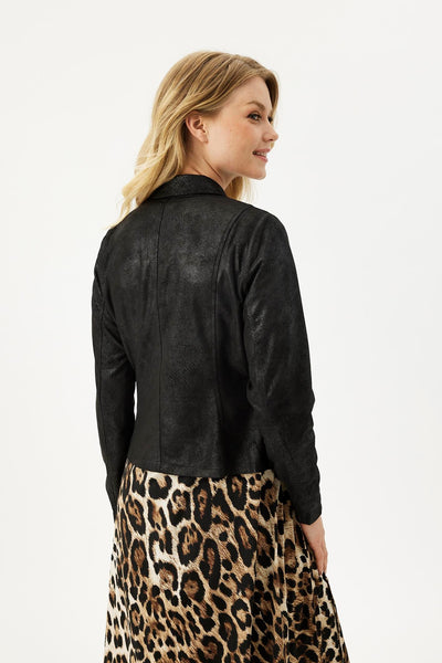Kvinne sett bakfra i svart jakke med tekstur, iført leopardmønstret skjørt.