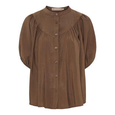 Brun bluse med knappelukking foran, rund krage og innsamlet stoff ved brystet. Puffermer.
