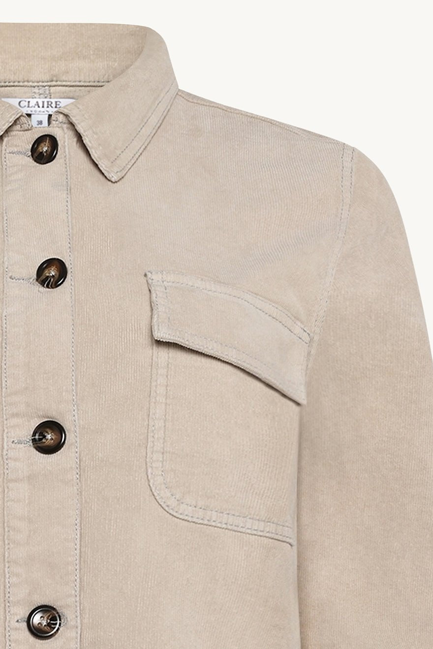 Beige cordskjorte med knappelukking, klassisk krage og brystlomme med klaff.