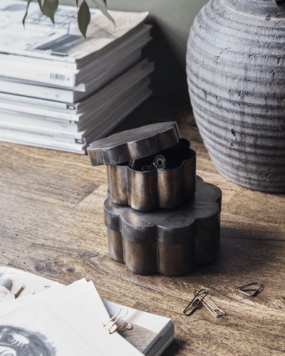 To beholdere med lokk i antikk brun, bølget design, står stablet på et bord med papirklips.