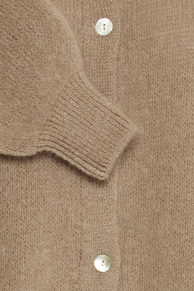 Beige strikket cardigan med ribbestrikkede mansjetter og synlige knapper.