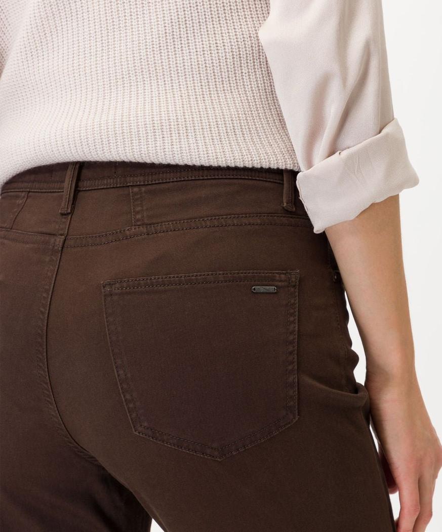 Nærbilde av brune bukser med lomme, kombinert med en hvit strikket topp.