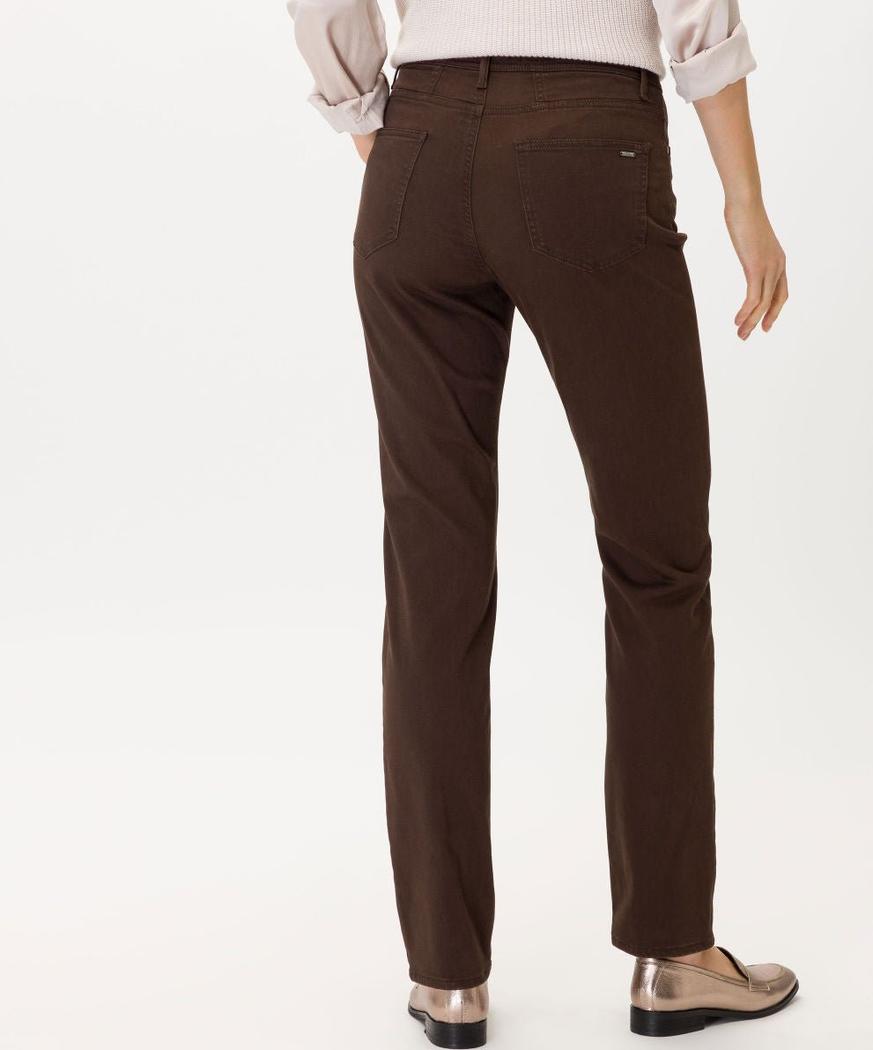 Brun stretchbukse sett bakfra, med metalliske loafers og en lys genser.