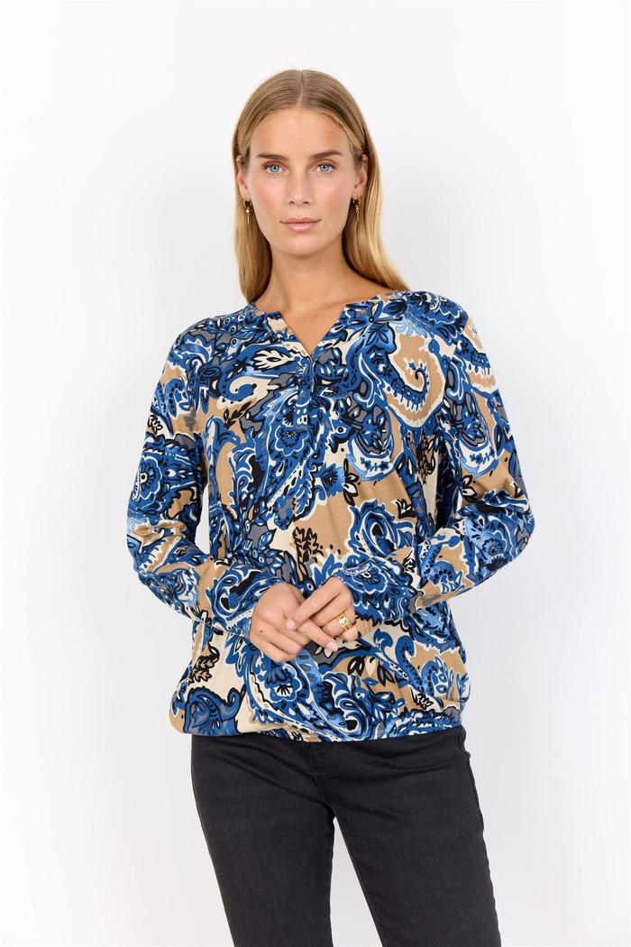Bluse med blått, svart og beige mønster, lange ermer og V-hals. Løs passform vises forfra.