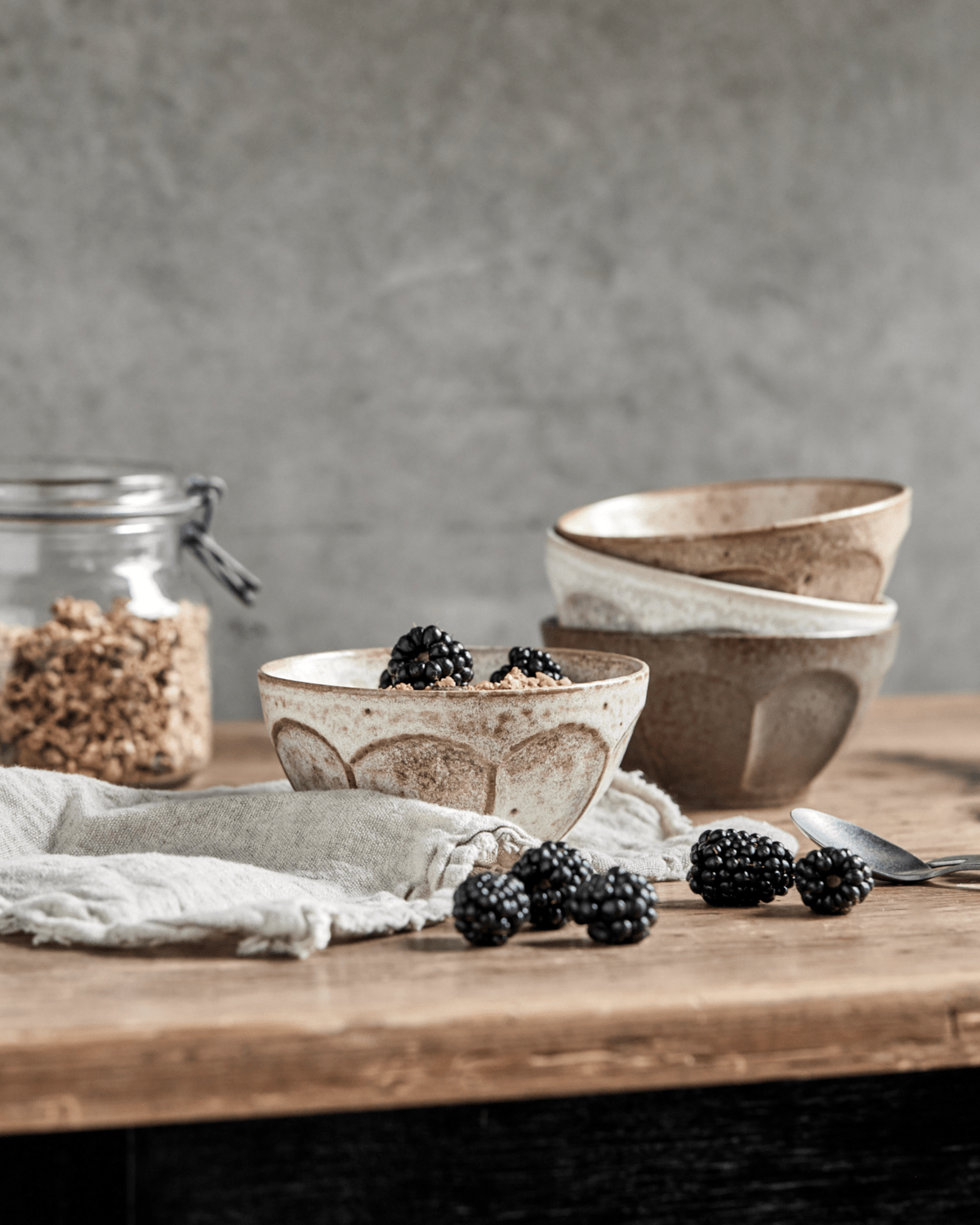 Tre skåler i off-white, beige og grønn med mønster. Skåler på trebord med bjørnebær og granola.