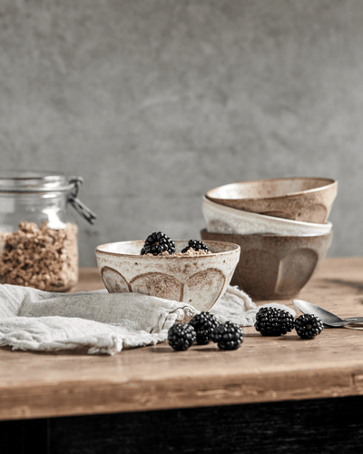 Tre skåler i off-white, beige og grønn med mønster. Skåler på trebord med bjørnebær og granola.