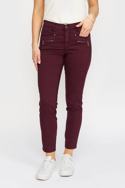 Burgunder slim-fit bukse med to glidelåslommer, hvit topp og hvite sneakers.