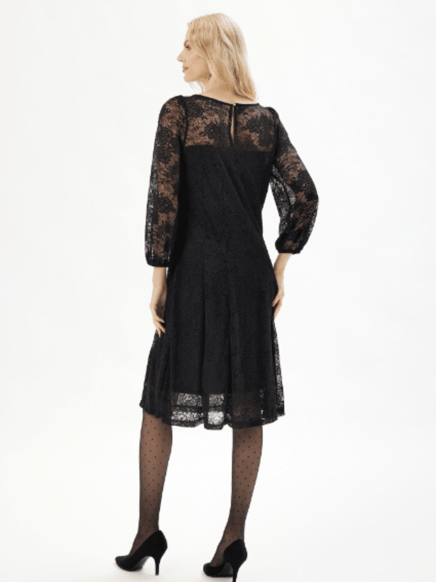 Svart kjole med blomsterblonder, lange ermer, knelang, sett bakfra.