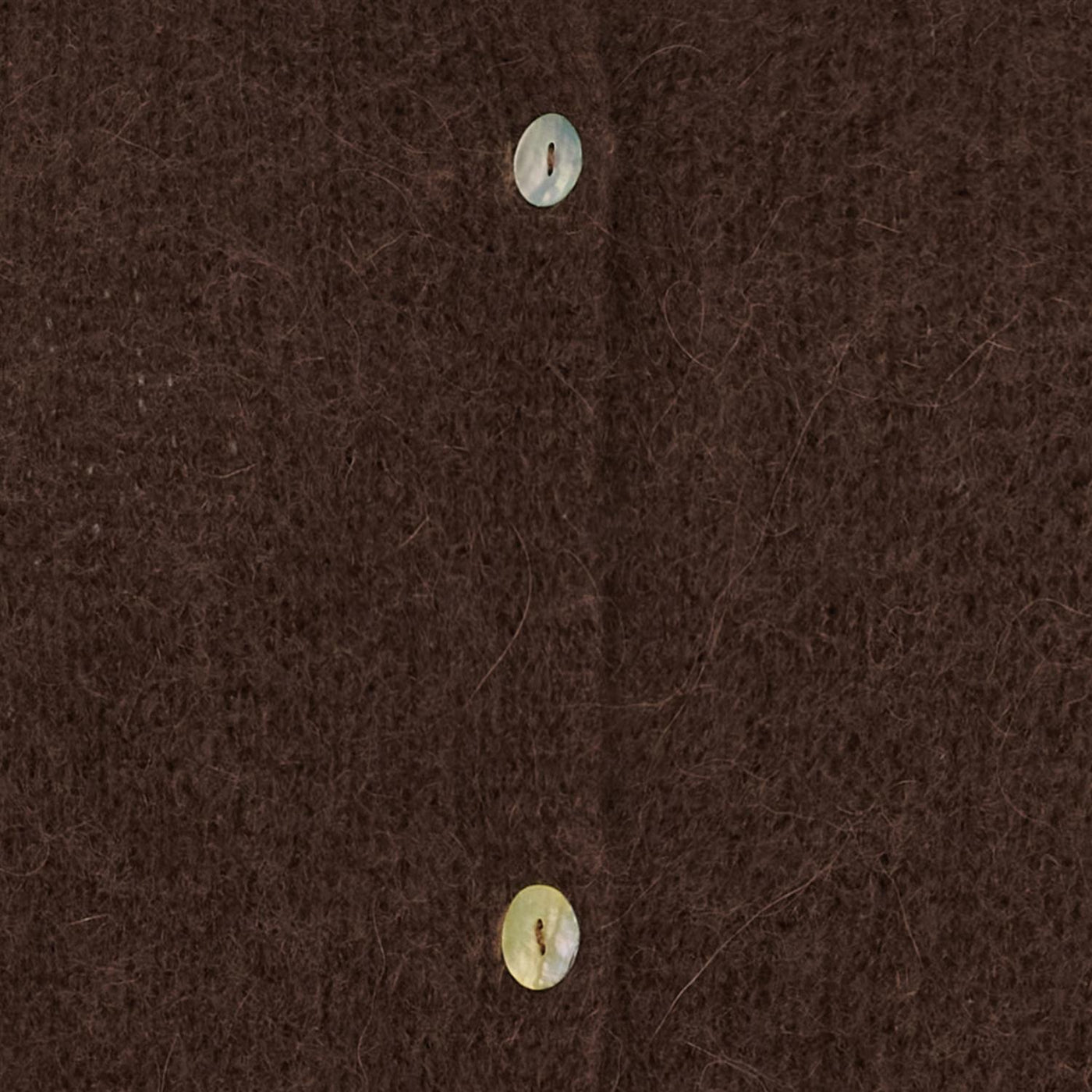 Nærbilde av brun strikket cardigan med knappelukking, viser tekstur og knapper.