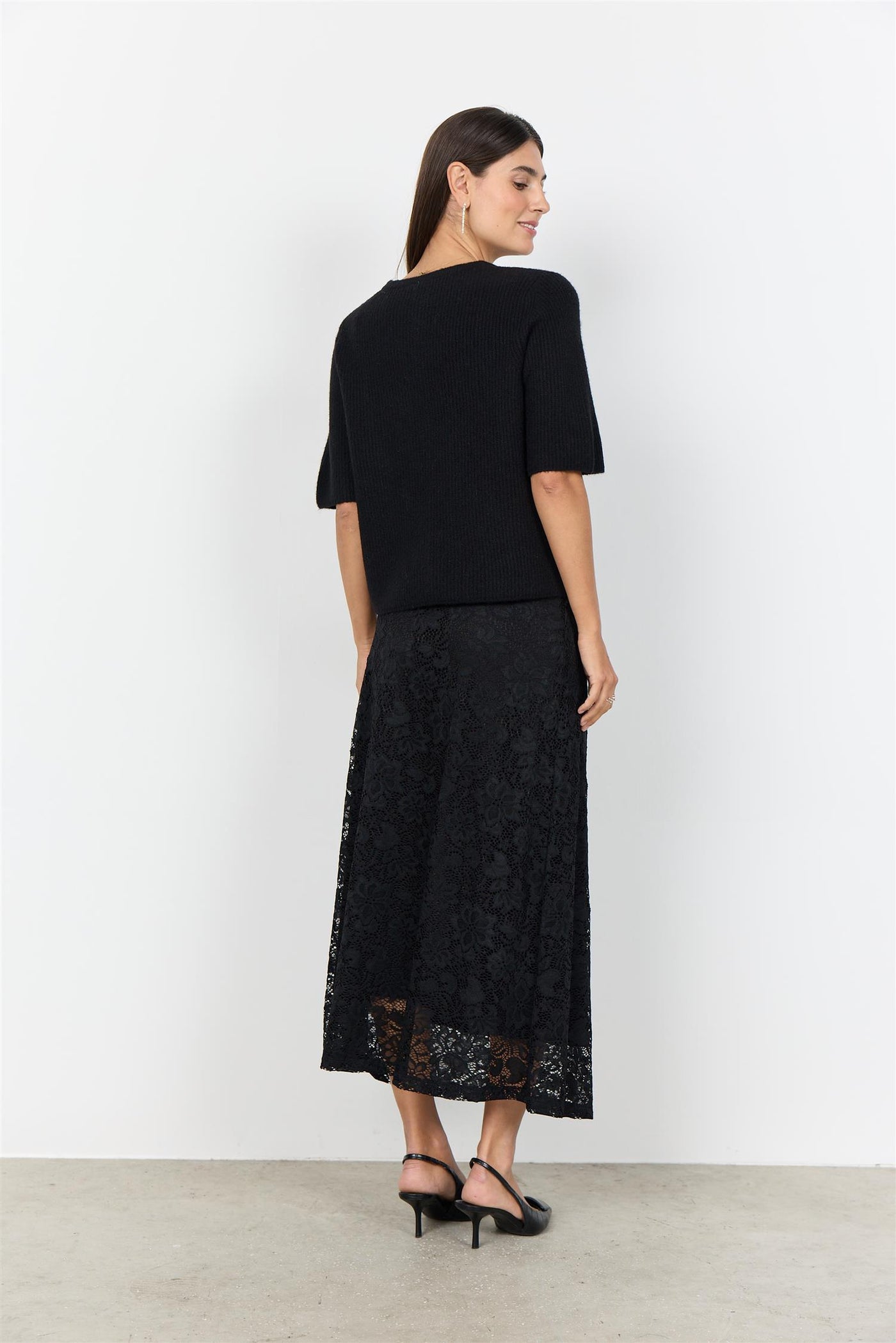 Sort plagg med korte ermer, strikket tekstur og runde blomsterknapper.