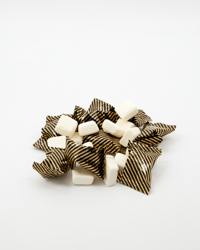 Individuelt innpakkede konfekter med svart og gullstripete innpakning på hvit bakgrunn.