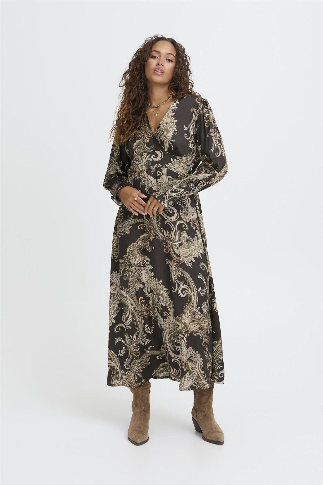 Modell i Sbolivia Paisley-kjole med lange ermer, V-hals og brune støvler.